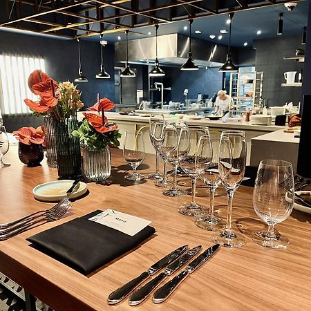 Royal Tulip Warsaw Centre 아파트 호텔 외부 사진 The photo shows a beautifully arranged dining area in a restaurant. There is a long wooden table set with elegant glassware, including wine glasses and water glasses. Each place setting includes polished silverware and a folded napkin with a card on 