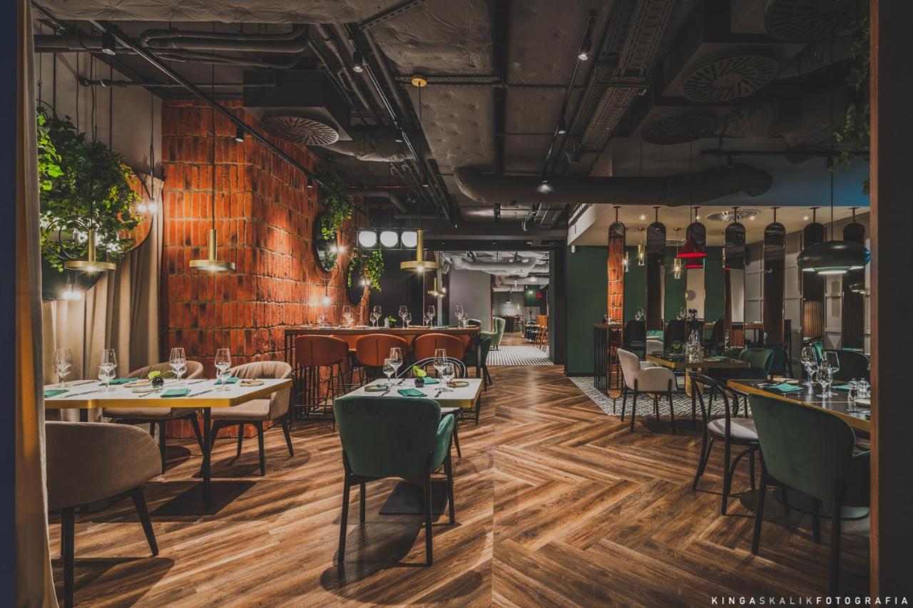 Royal Tulip Warsaw Centre 아파트 호텔 외부 사진 The photo shows the interior of a modern restaurant. The design features a mix of wood and industrial elements, with a warm and inviting atmosphere. There are wooden floors laid in a herringbone pattern, and the walls have a combination of brick and 