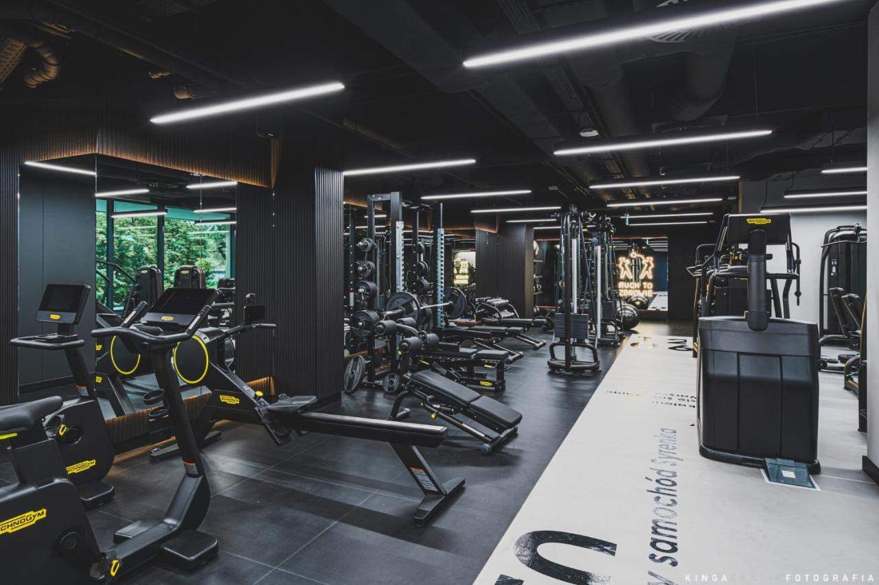 Royal Tulip Warsaw Centre 아파트 호텔 외부 사진 The photo shows a modern gym interior with a sleek design. It features a variety of exercise equipment, including weight machines, free weights, and cardio machines. The space is well-lit with overhead lighting, and there are large windows allowing n