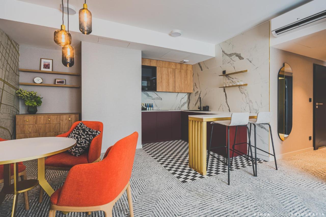 Royal Tulip Warsaw Centre 아파트 호텔 외부 사진 The photo shows a modern interior space, likely a kitchen and dining area. 

- **Kitchen Area**: The kitchen features a combination of wooden cabinets and a dark-colored countertop. There's a marble backsplash that adds a sleek touch. It has an open 
