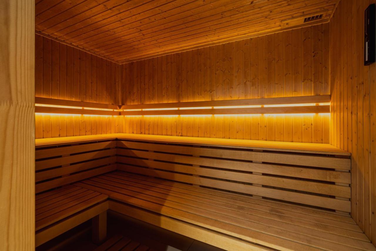 Royal Tulip Warsaw Centre 아파트 호텔 외부 사진 The photo shows the interior of a sauna. It features wooden walls and benches, creating a warm and cozy environment. The lighting is dim but highlights the wood's natural grain, contributing to a relaxing atmosphere. The design includes benches that 