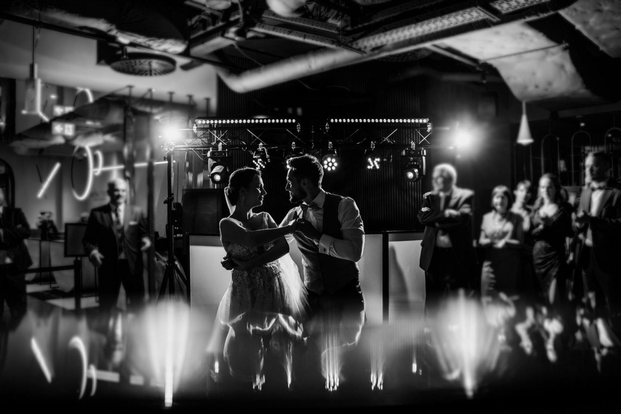 Royal Tulip Warsaw Centre 아파트 호텔 외부 사진 The photo depicts a couple dancing together in an elegant setting, likely during a celebration such as a wedding. The scene is captured in black and white, emphasizing the intimate atmosphere. In the background, there are people observing and enjoyin