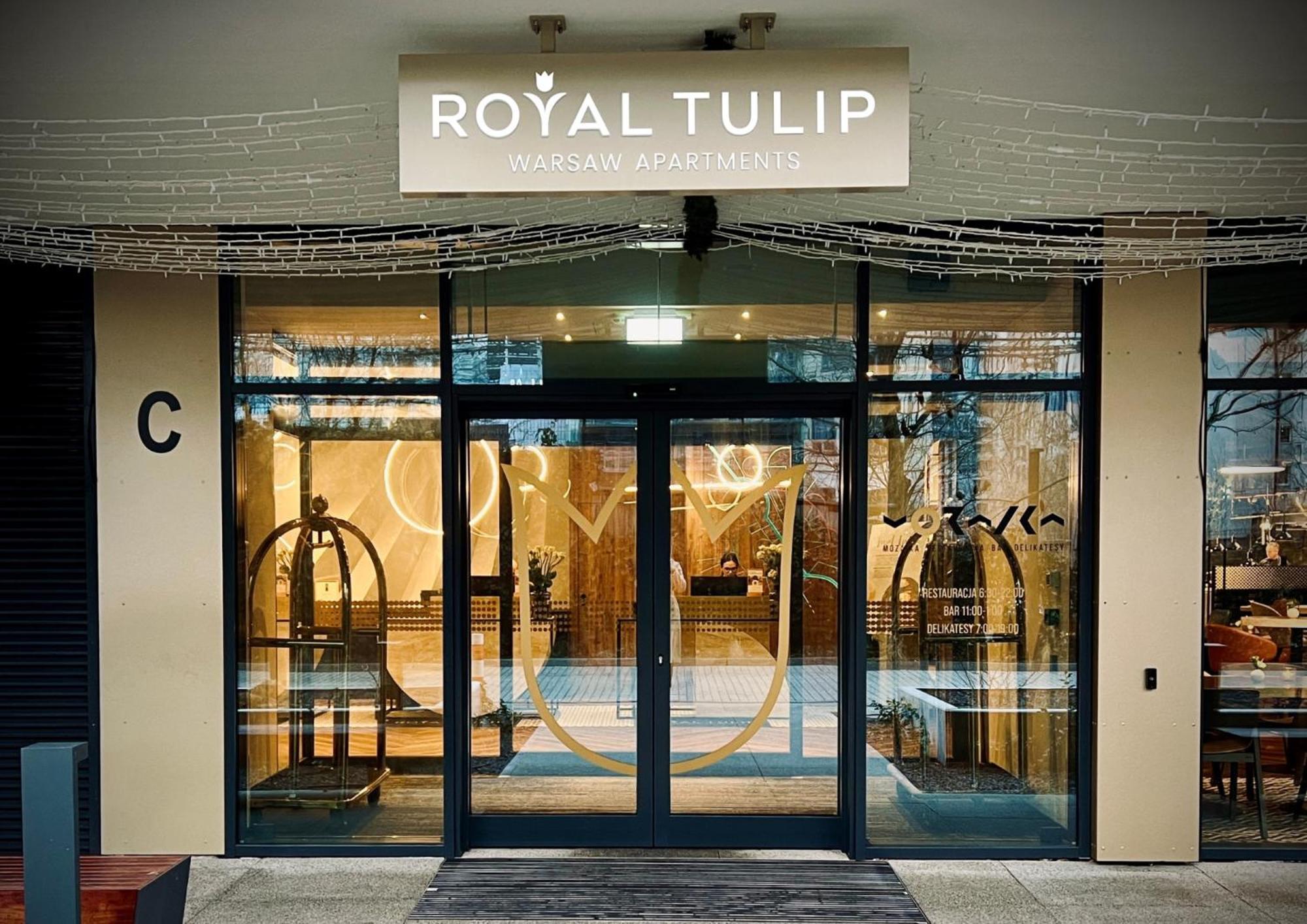 Royal Tulip Warsaw Centre 아파트 호텔 외부 사진 The photo shows the entrance to a hotel named "Royal Tulip." The facade features large glass doors that allow a view into the lobby area. There are decorative elements, including what appears to be luggage carts near the entrance. Above the doors is 