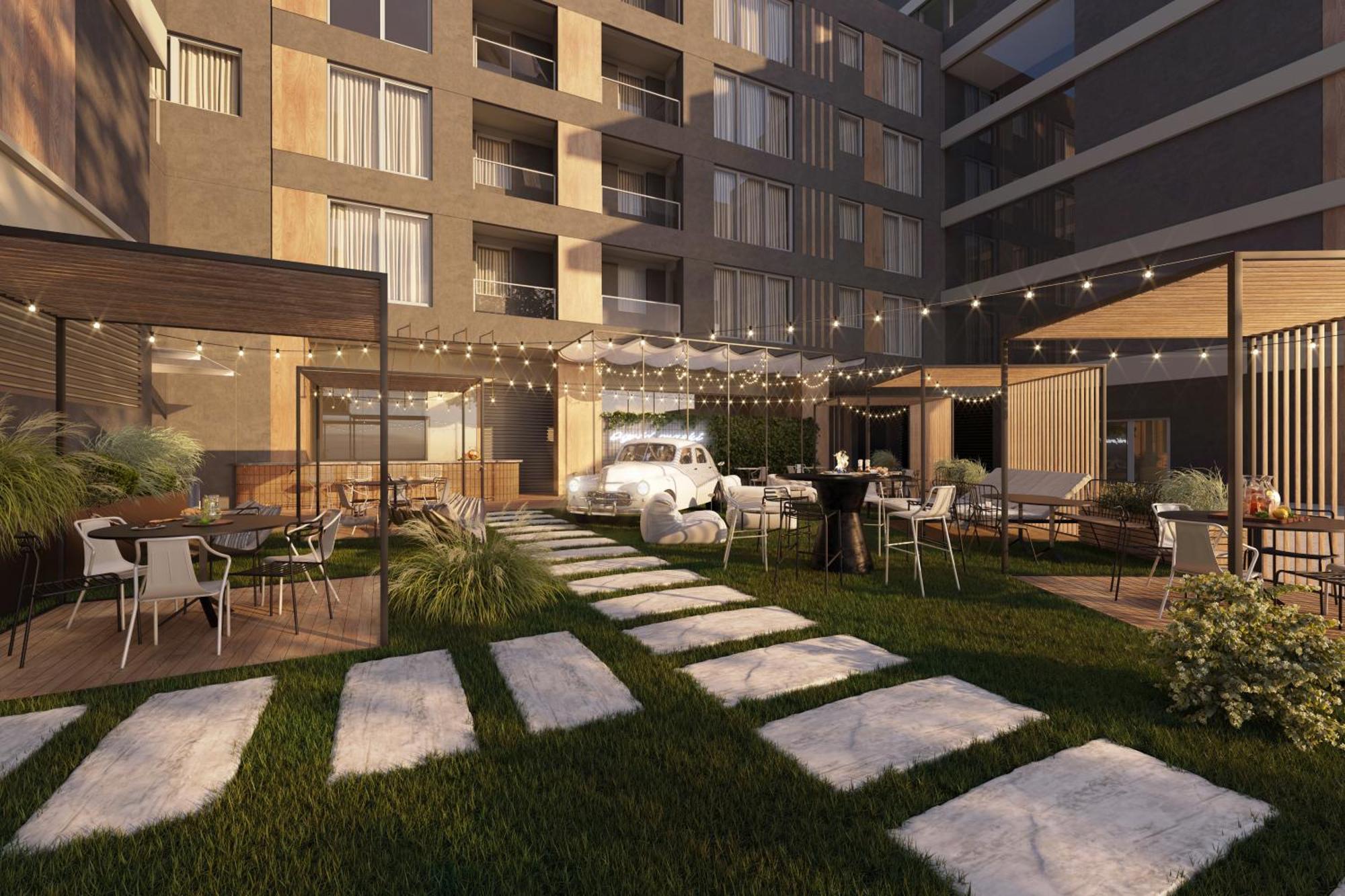 Royal Tulip Warsaw Centre 아파트 호텔 외부 사진 The photo shows a modern outdoor space in an apartment complex or residential building. It features a neatly landscaped area with a lawn, stone pathways, and neatly arranged outdoor seating. There are multiple tables and chairs, some under cozy canop