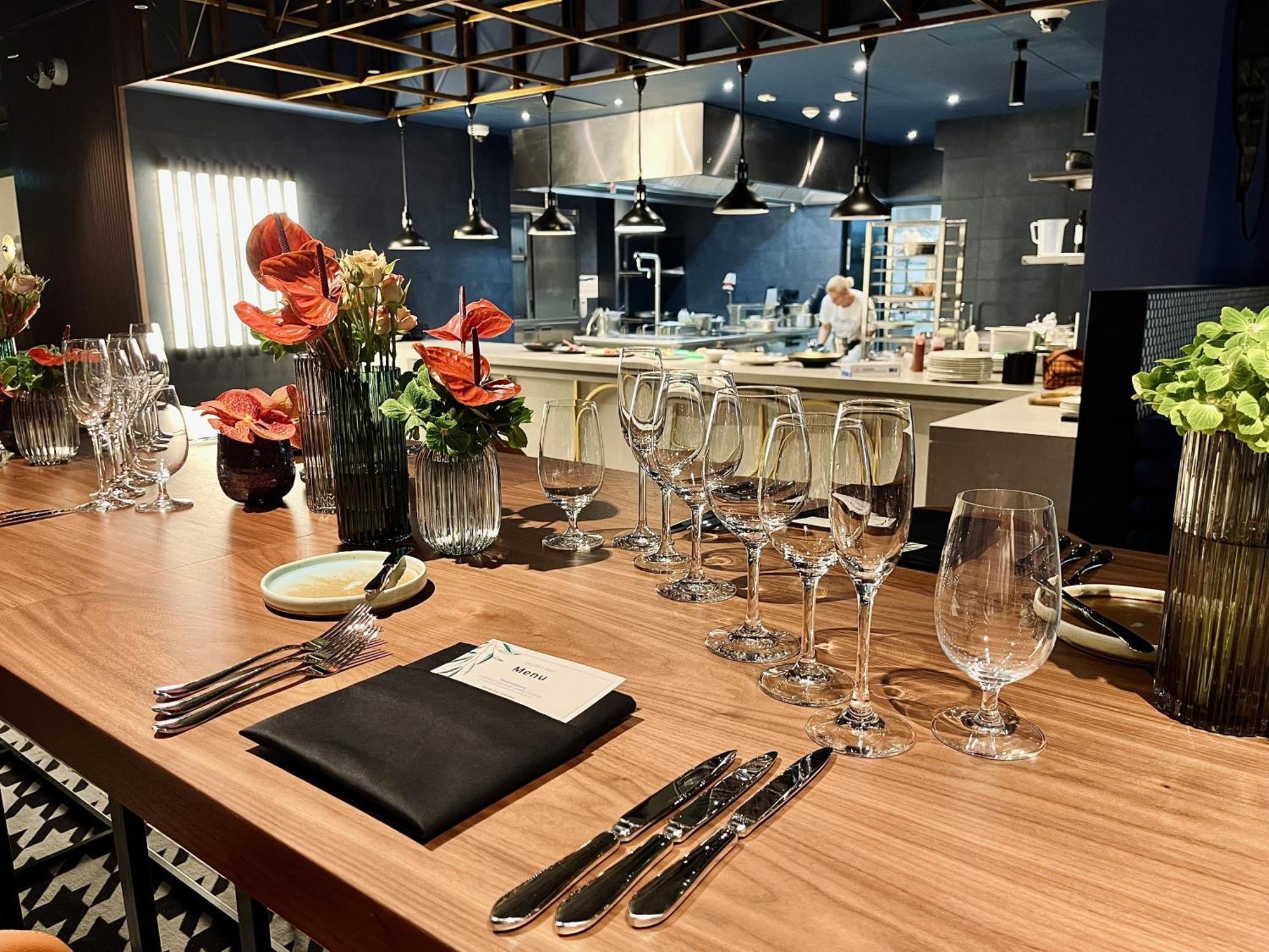 Royal Tulip Warsaw Centre 아파트 호텔 외부 사진 The photo shows a beautifully arranged dining area in a restaurant. There is a long wooden table set with elegant glassware, including wine glasses and water glasses. Each place setting includes polished silverware and a folded napkin with a card on 