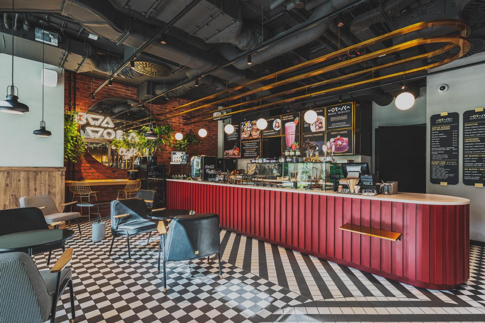 Royal Tulip Warsaw Centre 아파트 호텔 외부 사진 The photo shows a modern café interior. There is a prominent red counter that stretches across the space, where a variety of beverages and snacks are displayed. Behind the counter, there are menus and a selection of products. The flooring features a 